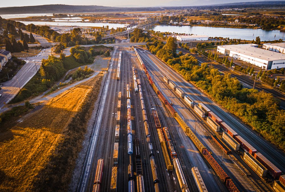 An overhead image of cargo trains on a railroad by a lake