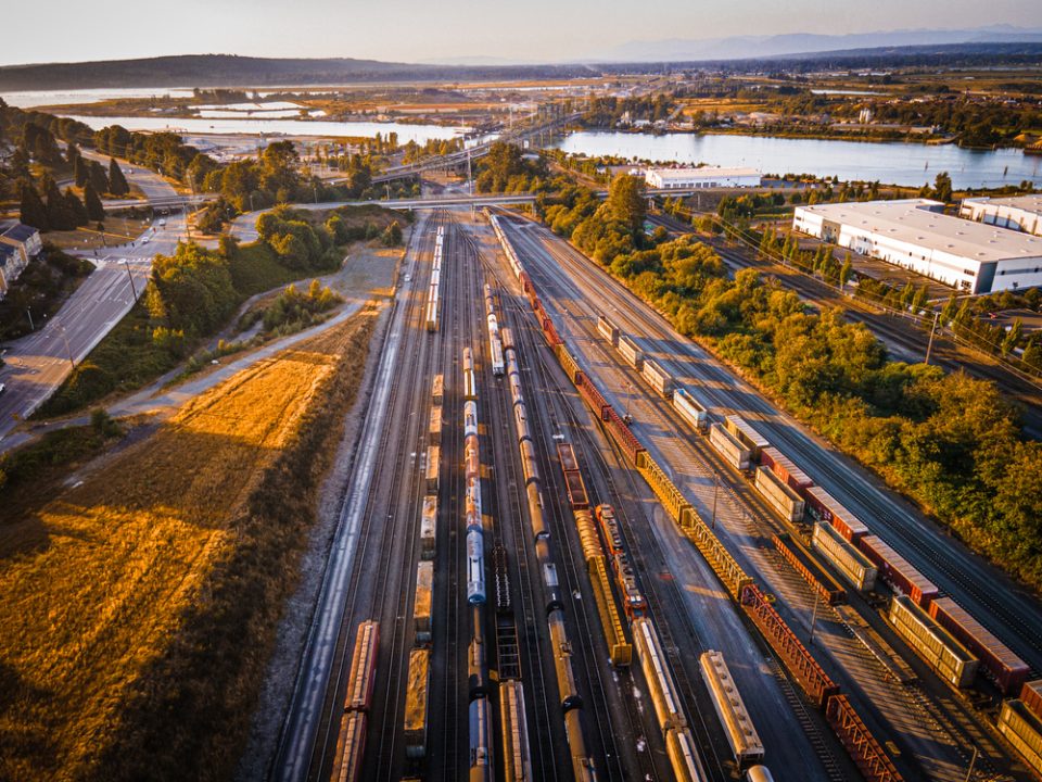 An overhead image of cargo trains on a railroad by a lake